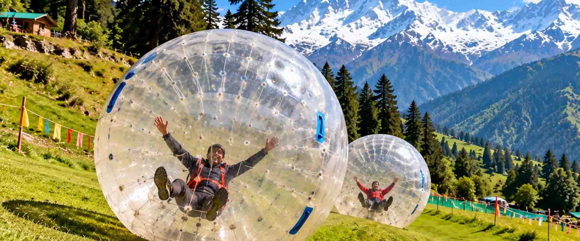 Zorbing in Himachal Pradesh with a giant inflatable ball on a green hillside surrounded by Himalayan mountains