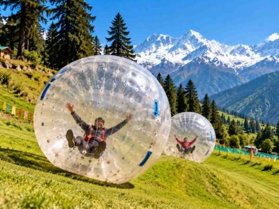 Zorbing in Himachal Pradesh with a giant inflatable ball on a green hillside surrounded by Himalayan mountains